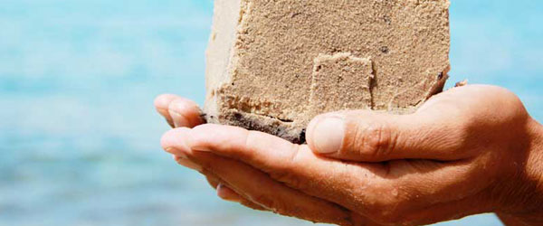A sandcastle being held with two hands